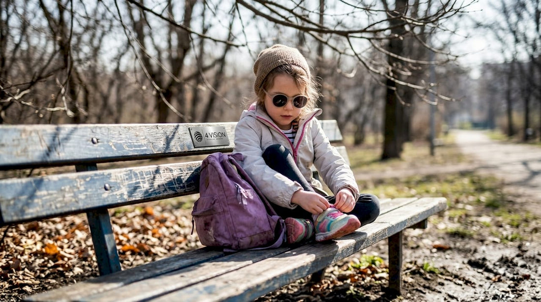 Child wearing sunglasses outdoors on park bench