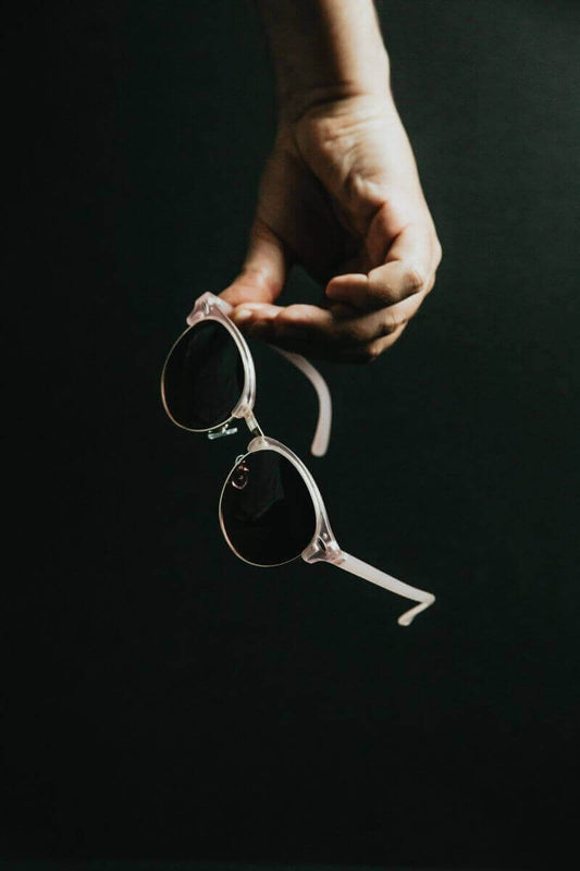 Person holding stylish sunglasses showcasing the latest trends in the Eyewear Industry.