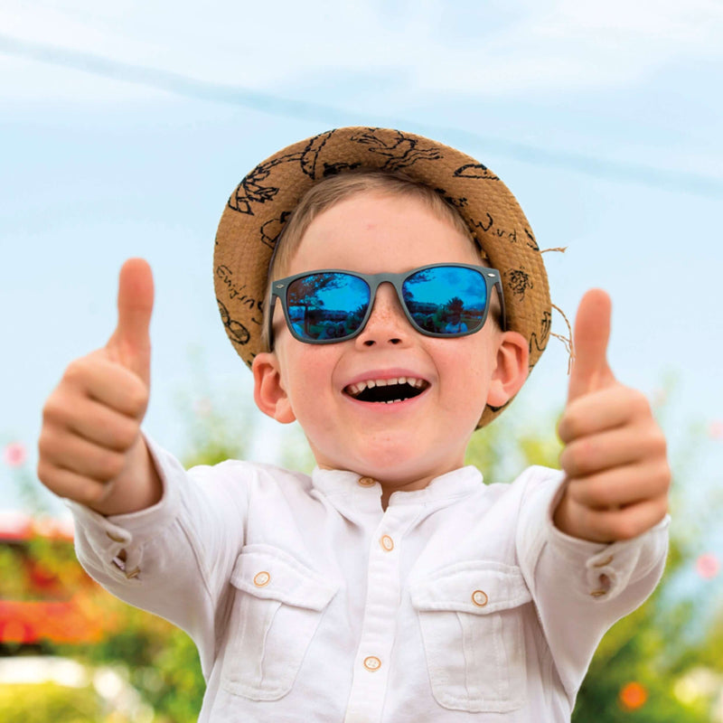 Cheerful child with sunglasses and a straw hat giving thumbs up in a vibrant summer setting.